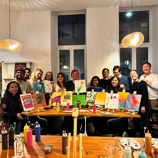 Group of people with their art pieces at a painting event.